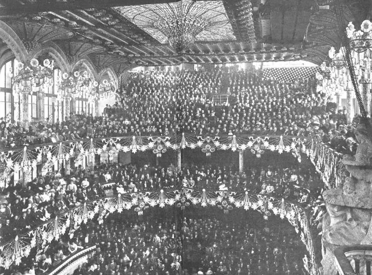 A black-and-white photograph of the Palau concert hall packed with people at its opening